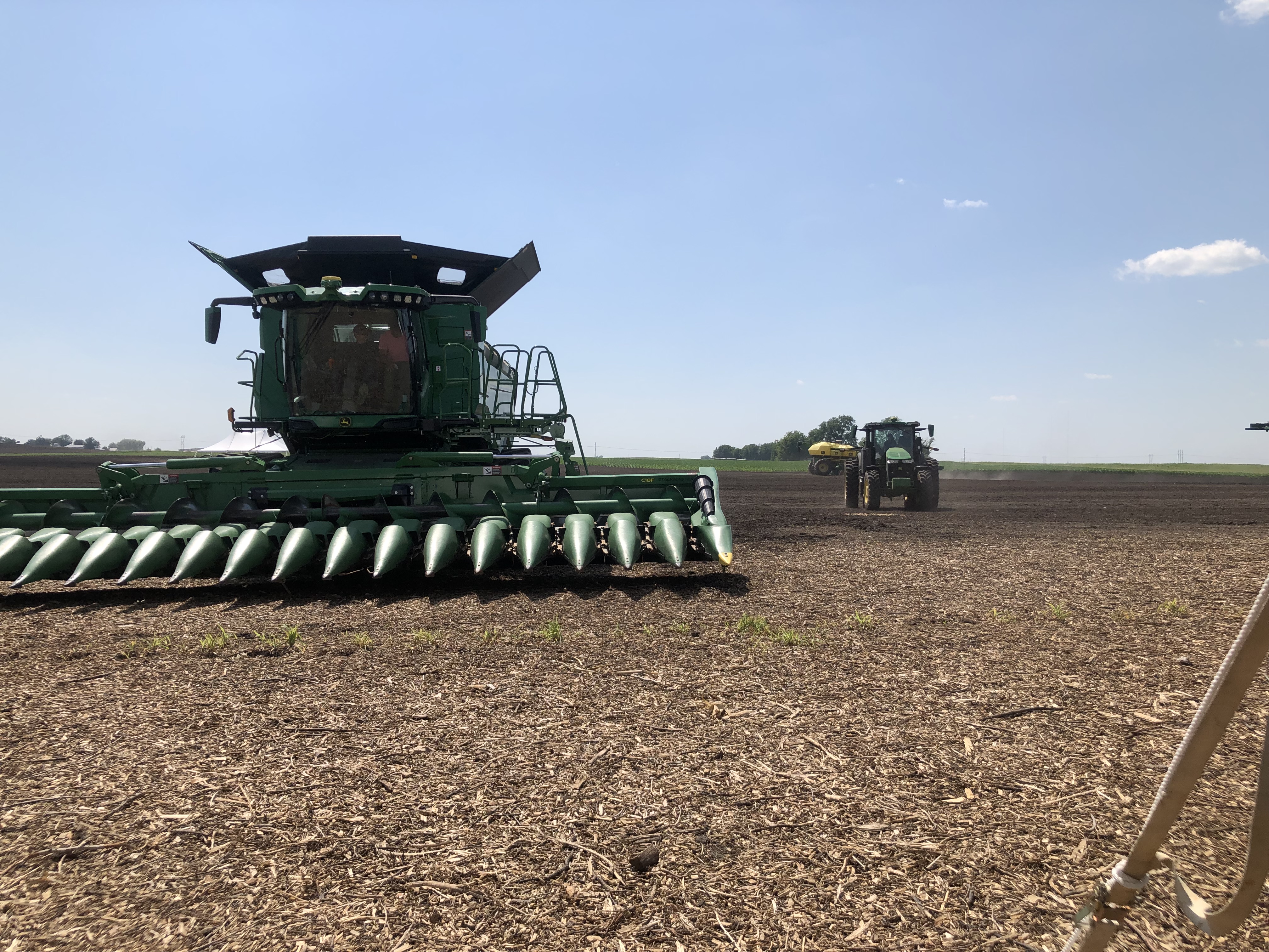 The front of a combine, with a tractor coming towards the photographer